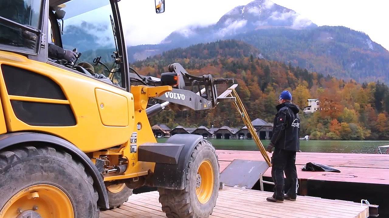 Mensch neben einem Bagger vor dem Königssee